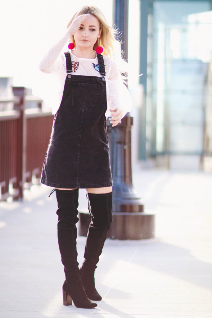 Alena Gidenko of modaprints.com styles a black overalls dress with over the knee boots