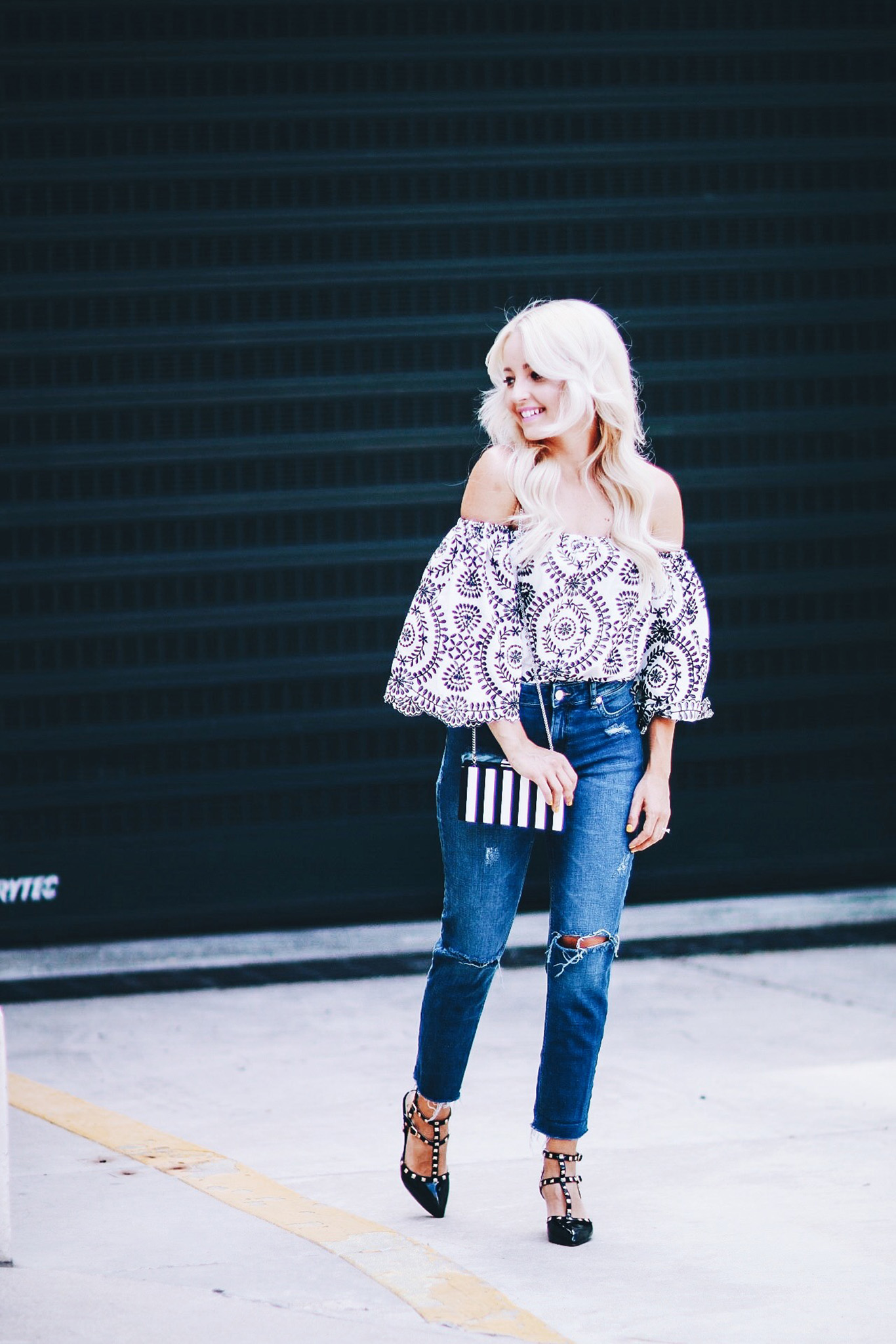 Alena Gidenko of modaprints.com styles an off the shoulder printed top with boyfriend jeans and studded black heels